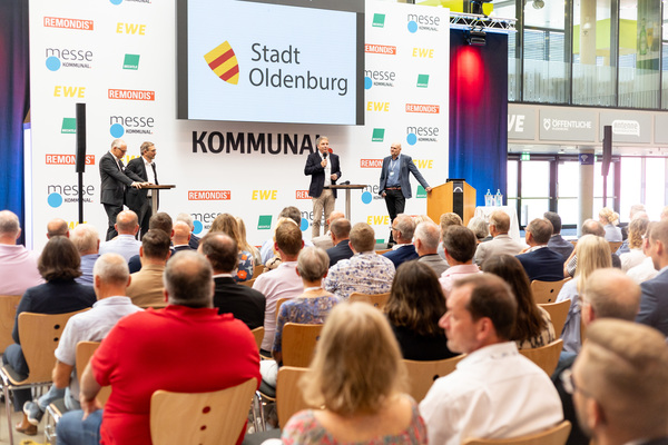 Vortragsbühne bei der Messe KOMMUNAL 2024. Vortrag von der Stadt Oldenburg mit Zuhörende im Vordergrund