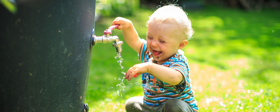 Ein kleines Kind erfreut sich am Wasser im Garten - Auch ein Aspekt der Trinkwasserversorgung