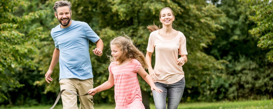 Glücklich Familie läuft mit Hund durch den Garten