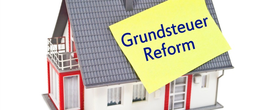 Haus mit Schild Grundsteuerreform auf dem Dach