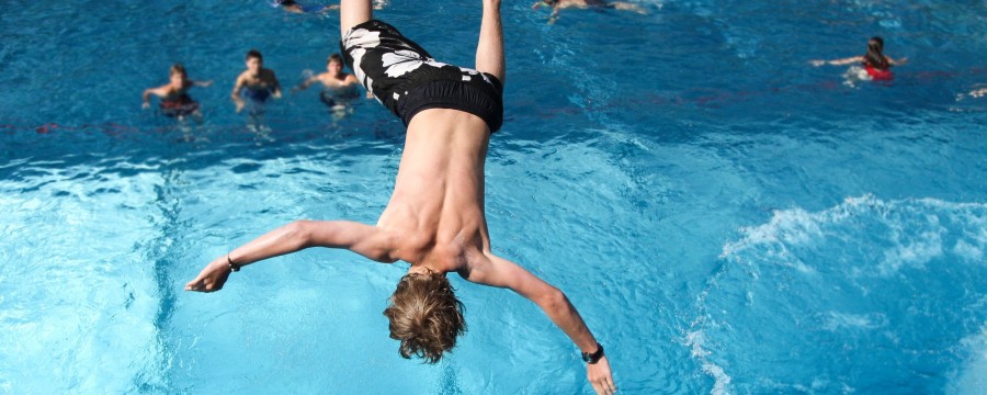 Junge springt im Freibad ins Wasser