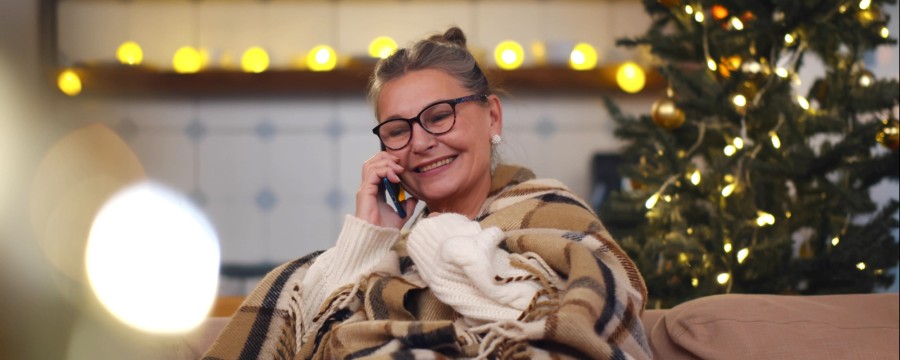 Frau telefoniert vor Weihnachtsbaum