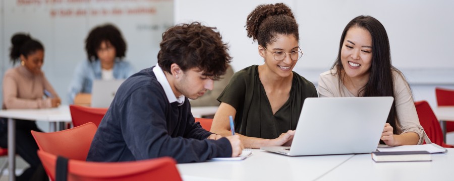 Schüler sitzen in Gruppen vor einem Laptop