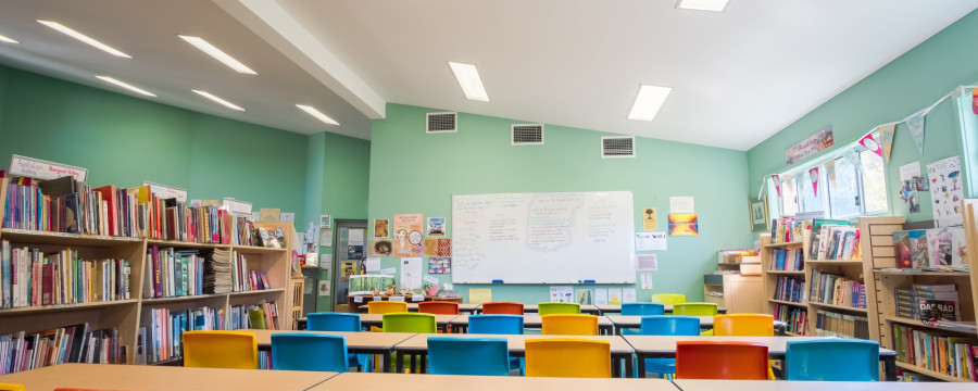 Leeres Klassenzimmer mit bunten Stühlen und Bücherregalen