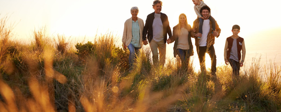 Mehrere Generationen einer Familie gehen bei Sonnenuntergang durch eine Wiese