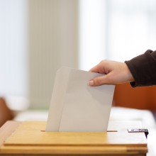 Wähler legt Stimmzettel in Wahlurne