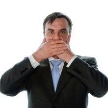 Verschwiegenheitspflicht: Mann hält sich Hände vor den Mund